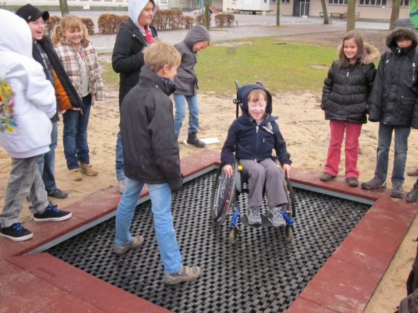 Junge im Rollstuhl hüpft auf dem Bodentrampolin 2012 auf einem Spielplatz